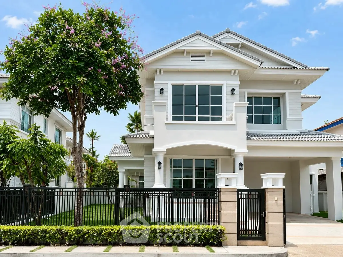 Stunning two-story white house with lush garden and modern fence in a serene neighborhood.