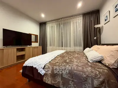 Cozy bedroom with modern decor and large TV, perfect for relaxation.