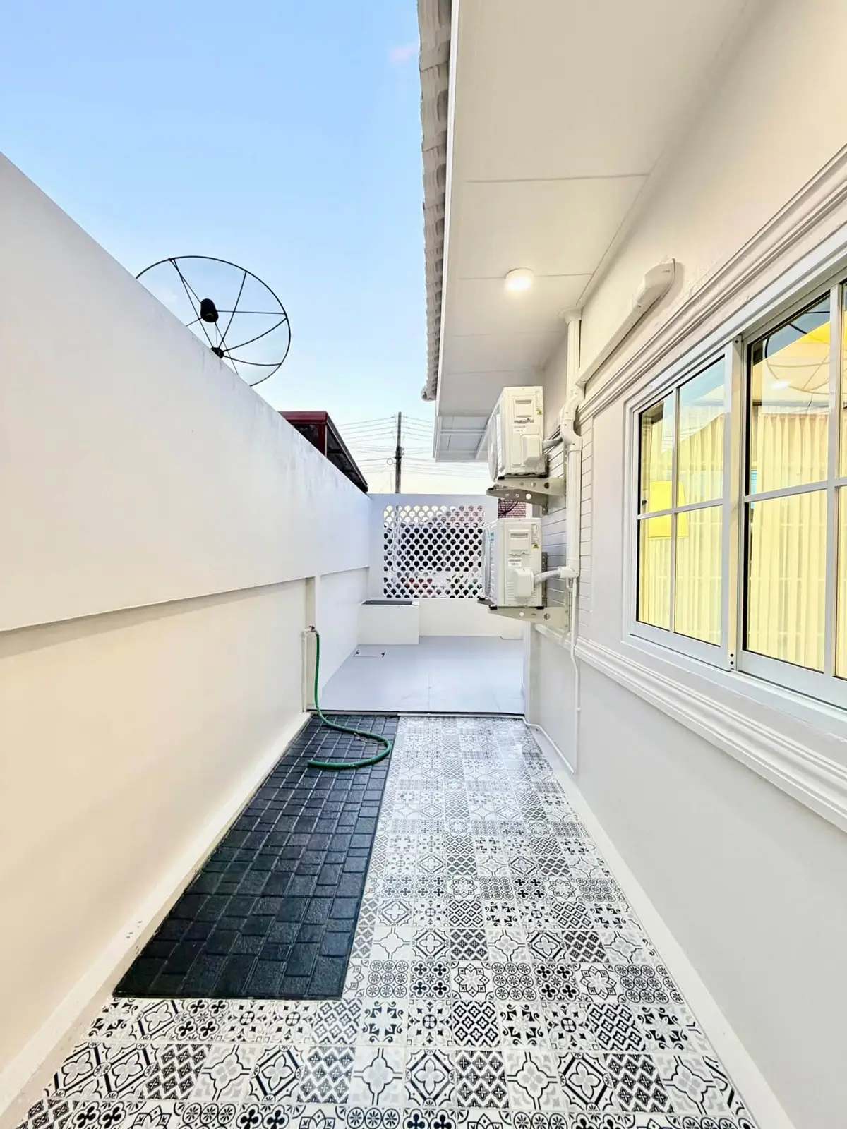 Charming outdoor space with patterned tiles and satellite dish, perfect for relaxation or utility use.