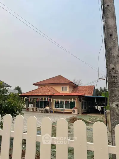 Charming two-story house with red-tiled roof and spacious yard, perfect for family living.