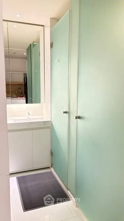 Modern bathroom with frosted glass doors and sleek white vanity