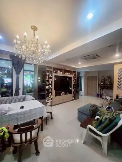 Spacious living room with elegant chandelier and modern decor, perfect for family gatherings.