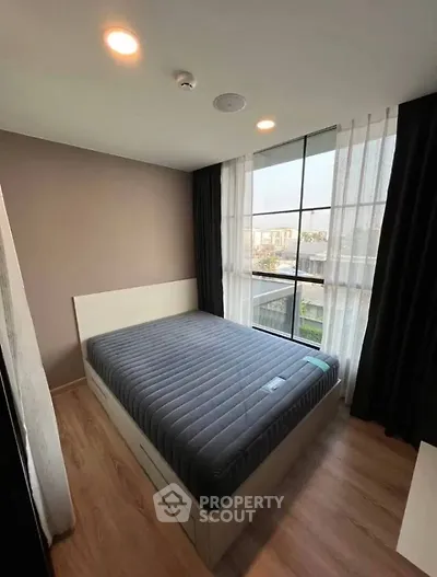 Cozy bedroom with large window and modern decor in a stylish apartment.