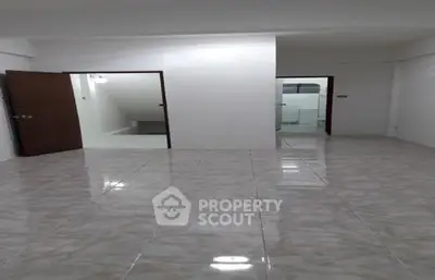 Spacious tiled room with open doorways and bright lighting, ideal for versatile use.