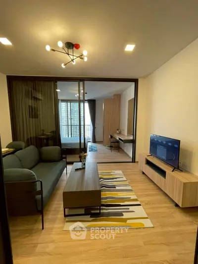 Modern living room with stylish decor and open layout leading to a bedroom with balcony view.