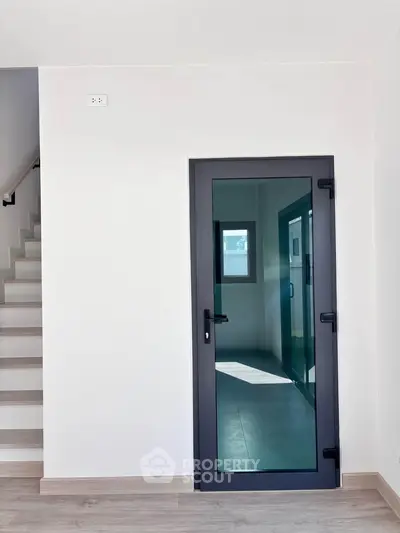 Modern interior with sleek glass door and staircase, minimalistic design.