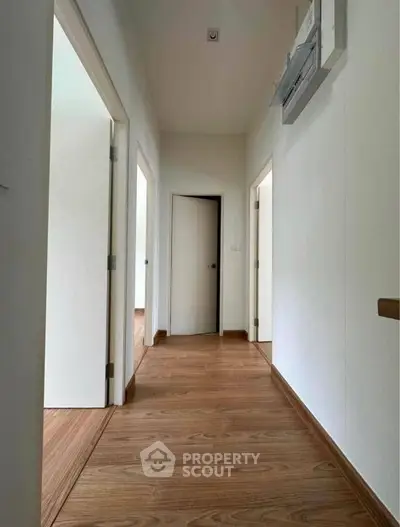 Spacious hallway with wooden flooring and white doors in modern home