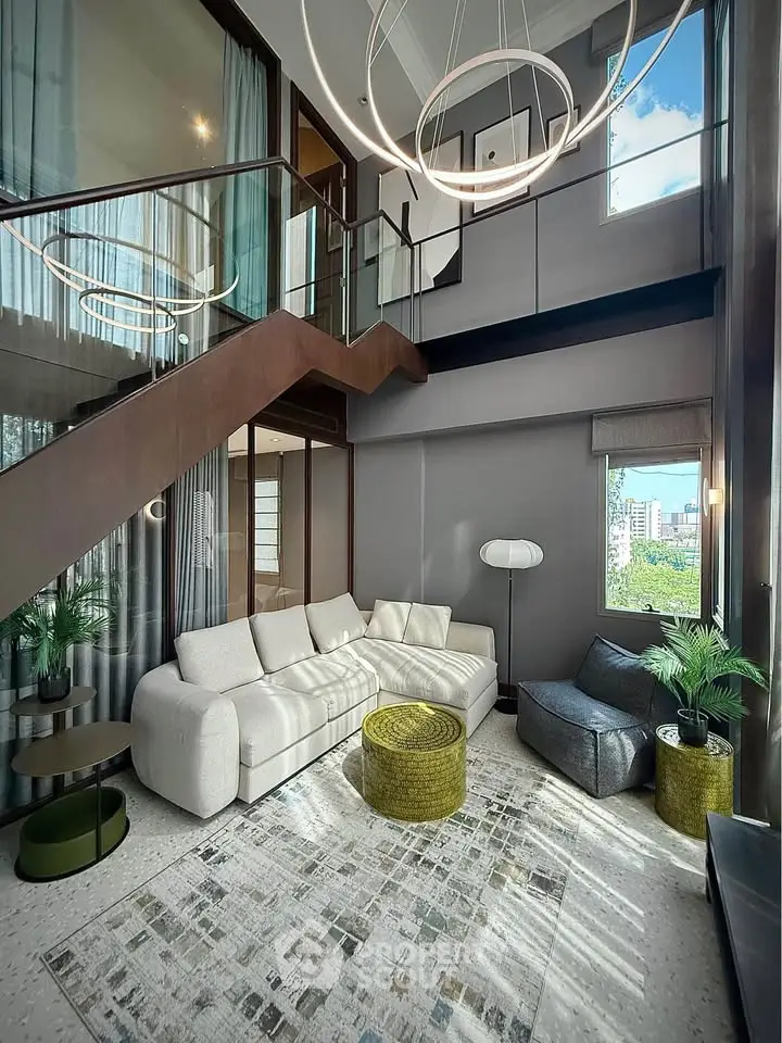 Stunning modern living room with high ceilings, elegant staircase, and chic furnishings in a luxury apartment.