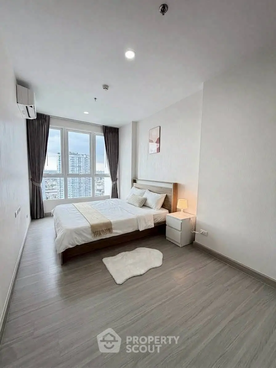 Modern bedroom with city view, featuring a cozy bed and stylish decor in a high-rise apartment.