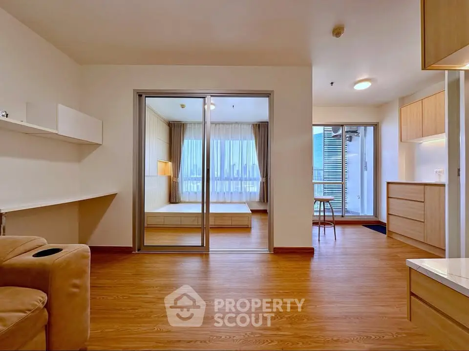 Spacious modern apartment with open layout and wooden flooring, featuring a cozy bedroom and ample natural light.