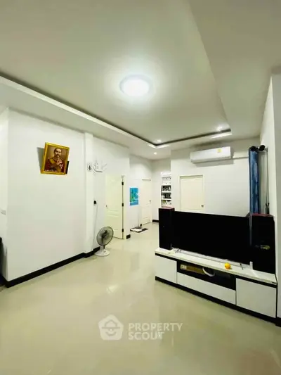 Spacious modern living room with sleek white decor and entertainment center.