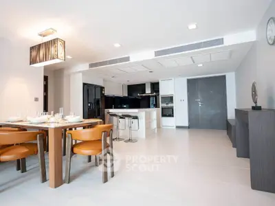 Spacious modern living room with open kitchen and elegant dining area, featuring sleek furniture and contemporary design.