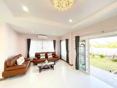 Spacious living room with elegant chandelier and modern brown leather sofas, offering a bright and inviting atmosphere.
