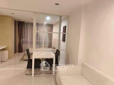 Modern living room with sleek white furniture and glass partition in stylish apartment.