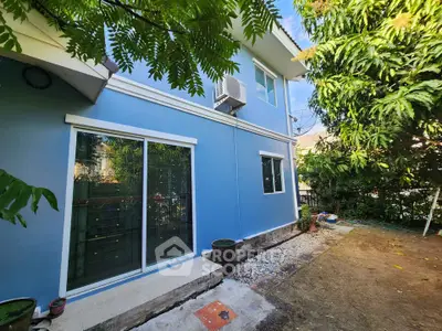 Charming blue two-story house with lush garden and sliding glass doors