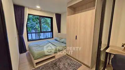 Cozy bedroom with large window and modern wardrobe overlooking lush greenery.