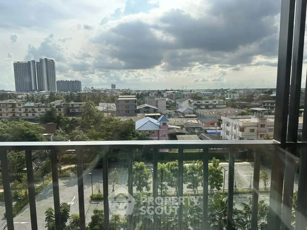 Stunning cityscape view from a high-rise balcony with lush greenery and urban skyline.