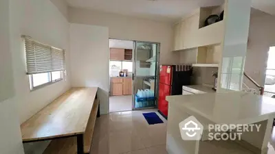 Modern kitchen with sleek countertops, red fridge, and ample natural light, perfect for culinary enthusiasts.