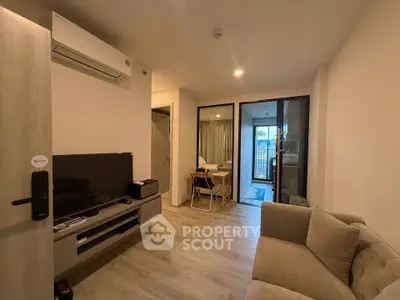 Modern living room with cozy sofa and TV, leading to a balcony with natural light.