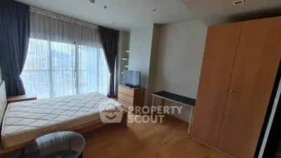Spacious bedroom with city view, featuring a large window, wooden furniture, and modern decor.