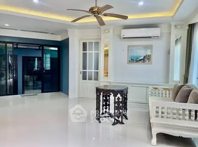 Spacious living room with elegant decor and ceiling fan, featuring a cozy seating area and modern air conditioning.