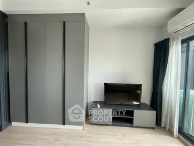 Modern living room with sleek TV stand and built-in wardrobe, featuring natural light and minimalist design.