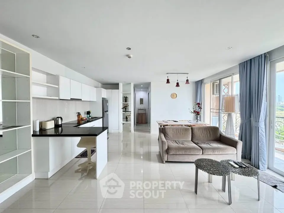 Spacious open-plan living room with modern kitchen and balcony view.