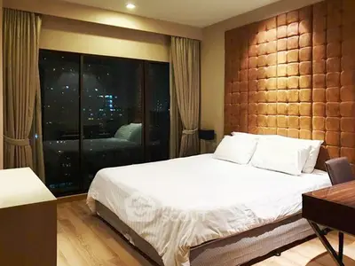 Luxurious bedroom with city view, featuring elegant decor and ambient lighting for a cozy atmosphere.