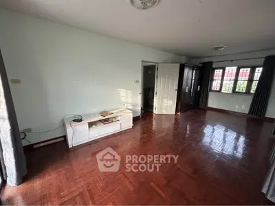 Spacious living room with polished wood flooring and natural light