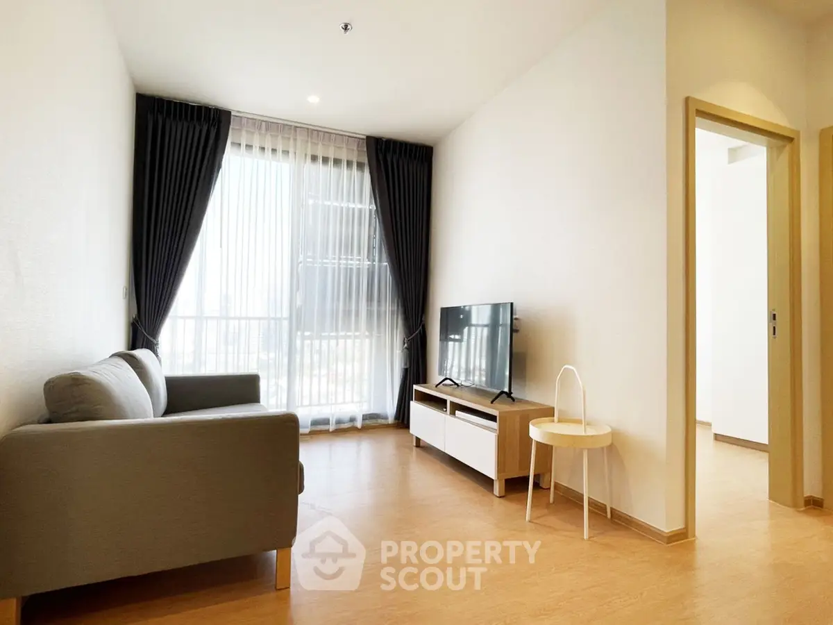 Modern living room with sleek furniture and large window, perfect for urban living.