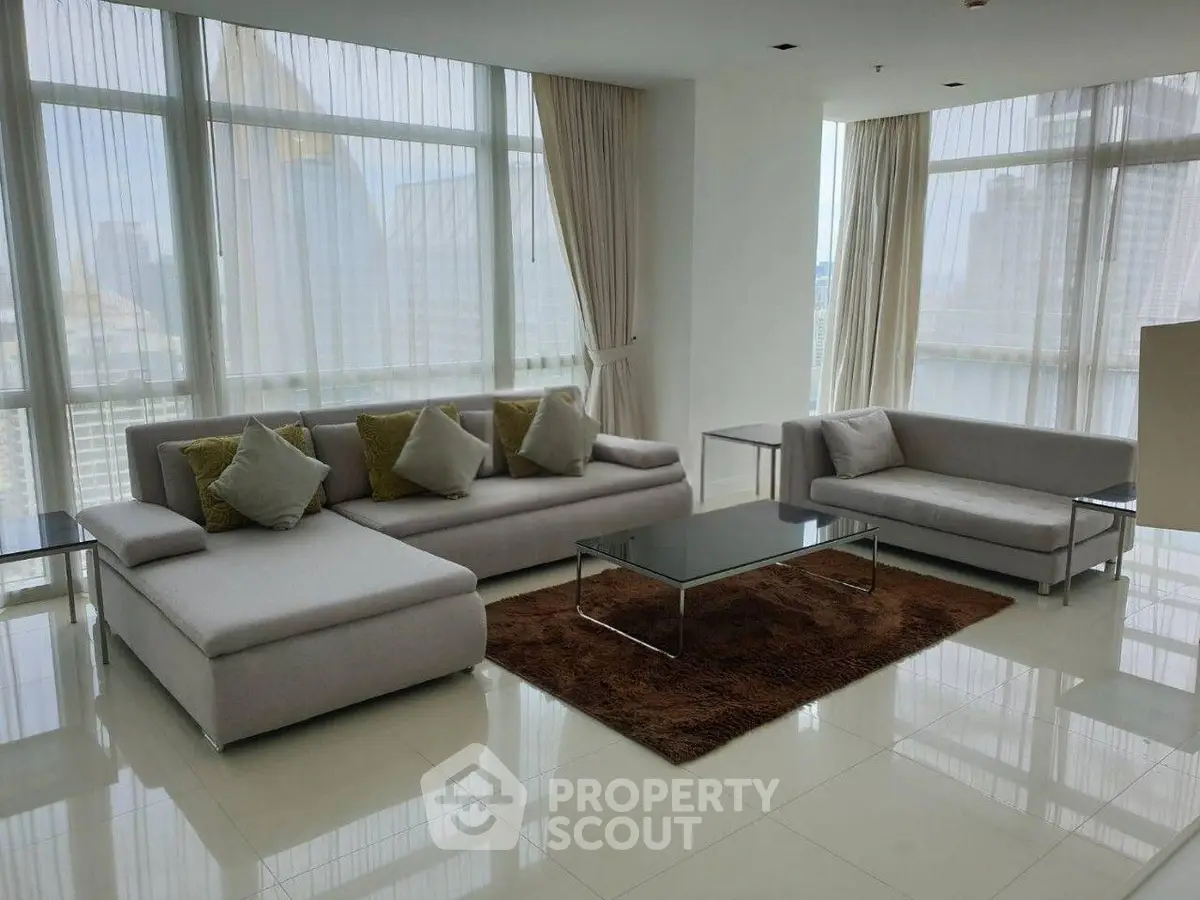 Spacious modern living room with large windows and elegant furniture in a high-rise apartment.
