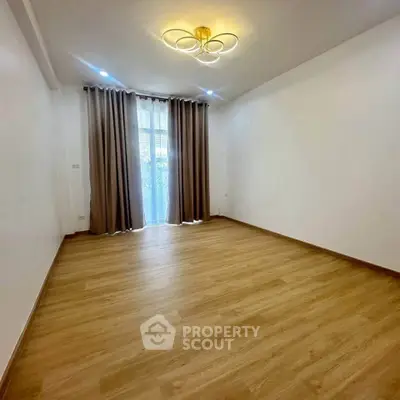Spacious empty room with elegant wooden flooring and modern lighting, perfect for customization.