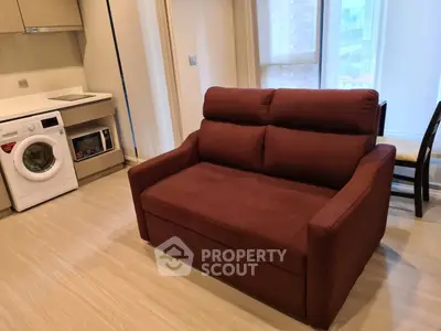 Modern living room with red sofa and integrated kitchen appliances in a cozy apartment.