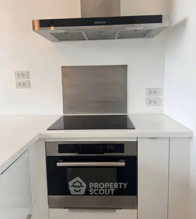 Modern kitchen with sleek built-in oven and stovetop, featuring minimalist design and stainless steel accents.