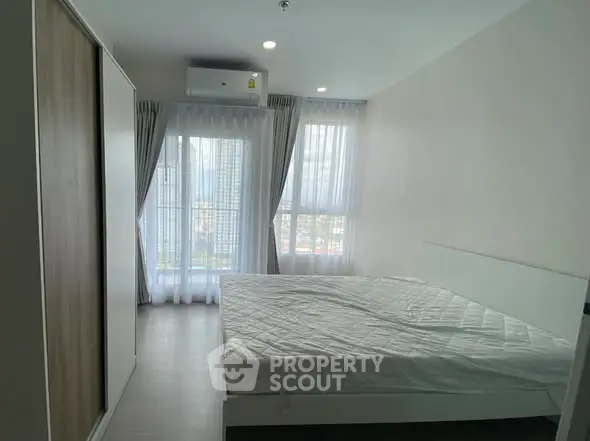 Spacious bedroom with large windows and modern design in a high-rise apartment.