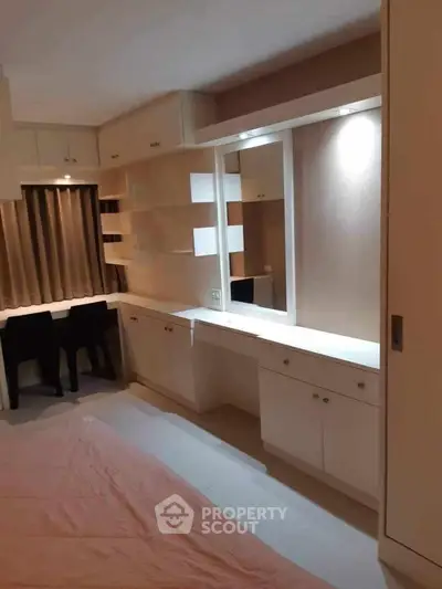 Modern bedroom with built-in storage and study area, featuring sleek cabinetry and ambient lighting.