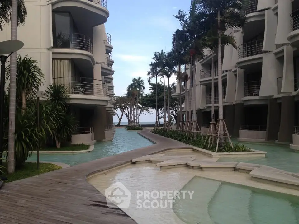 Luxurious modern apartment complex with stunning poolside view and lush palm trees.