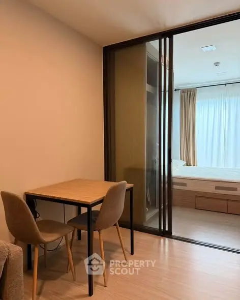 Modern apartment interior with cozy dining area and sliding glass doors to bedroom.