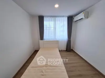 Minimalist bedroom with single bed, air conditioning, and large window with curtains.