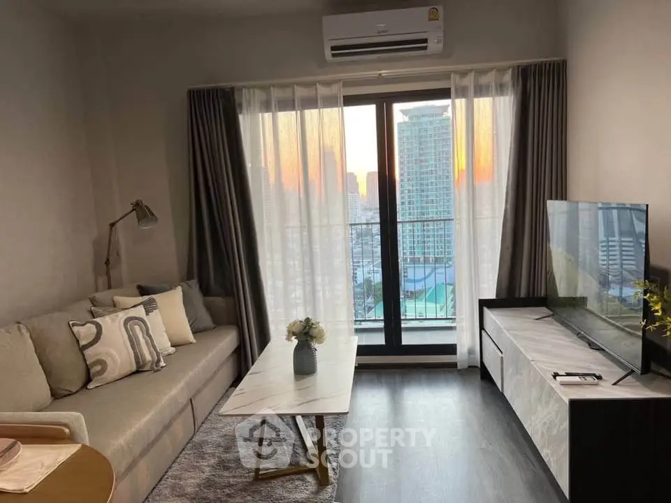 Modern living room with city view, featuring stylish furniture and large windows for natural light.
