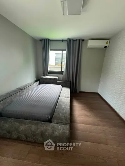 Modern bedroom with sleek design, featuring a cozy bed, wooden flooring, and air conditioning for ultimate comfort.