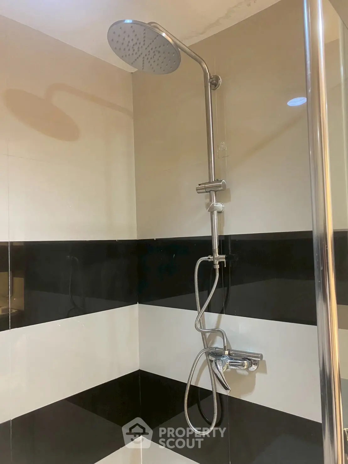 Modern bathroom with sleek shower fixture and stylish black and white tiles.
