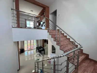 Modern duplex interior with stylish staircase and open living area, featuring sleek metal railings and large windows.