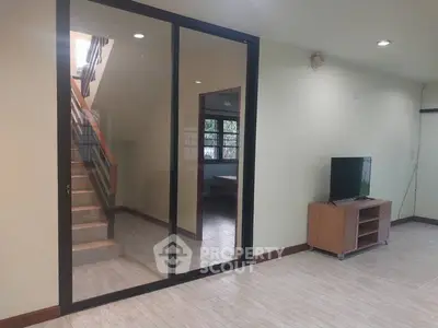 Spacious living room with modern staircase and TV setup, perfect for family gatherings.