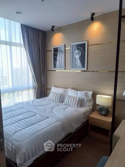 Modern bedroom with stylish decor and large window offering natural light.