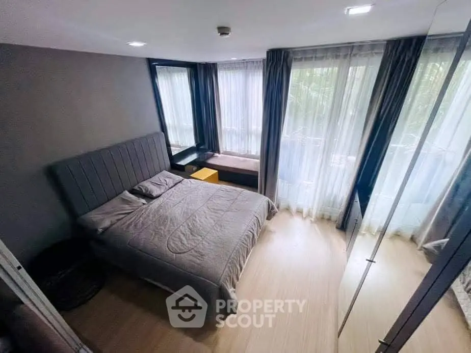 Modern bedroom with large windows and stylish decor in a cozy apartment.