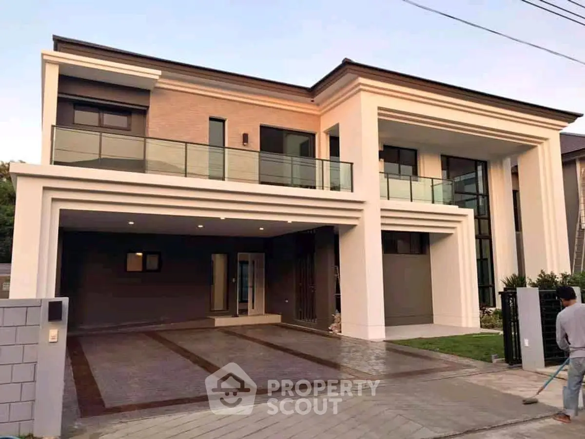 Modern two-story house with spacious driveway and elegant balcony.