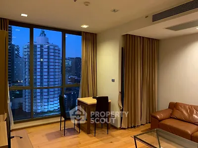 Modern living room with city view, featuring leather sofa and dining area.