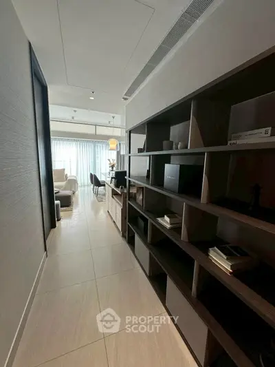 Modern hallway leading to a bright living room with stylish furniture and decor.