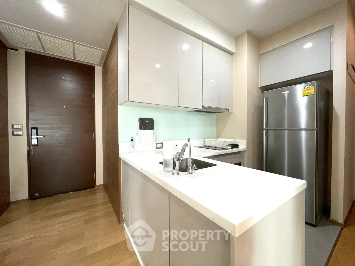 Modern kitchen with sleek cabinetry and stainless steel appliances in a stylish apartment.